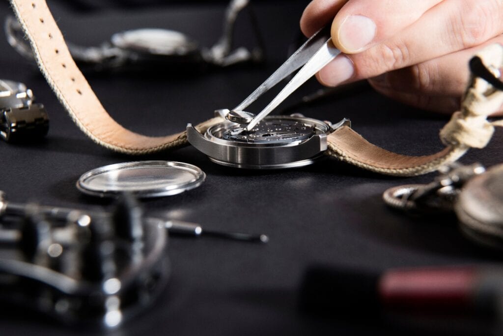 Detail of the work of a watchmaker who replaces a battery / Close up of replacing a watch battery with watchmaker tools