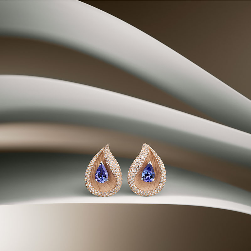 Zwei tropfenförmige Ohrringe in Gold mit blauen Edelsteinen und funkelnden Steinen