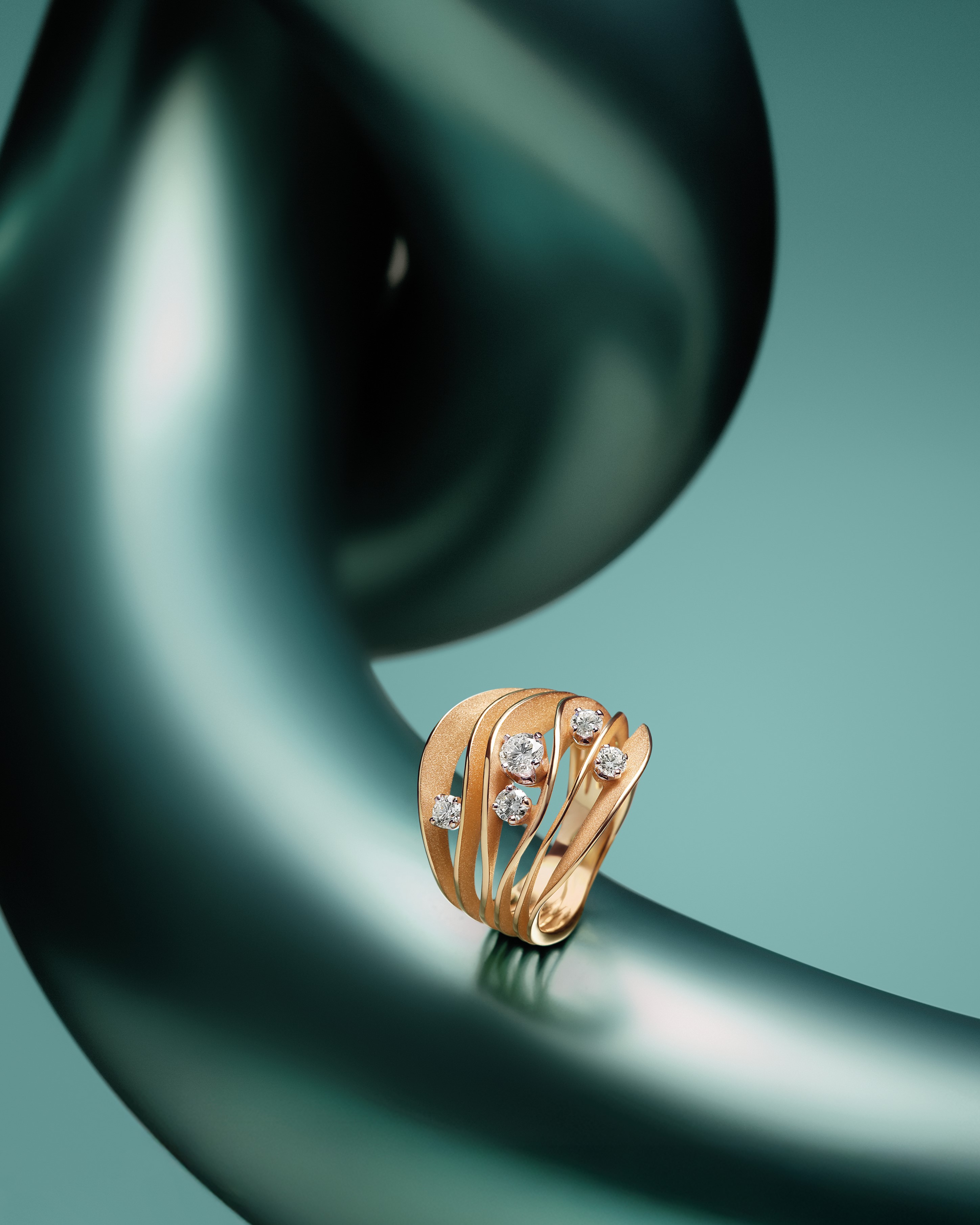 Ein goldener Ring mit mehreren Diamanten liegt an einer eleganten geschwungenen Struktur