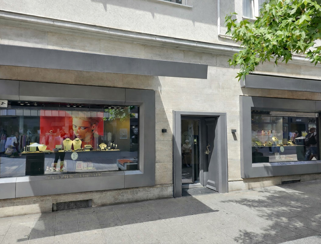 Schaufenster eines Schmuckladens mit goldenen Halsketten und einem Werbeplakat mit Model