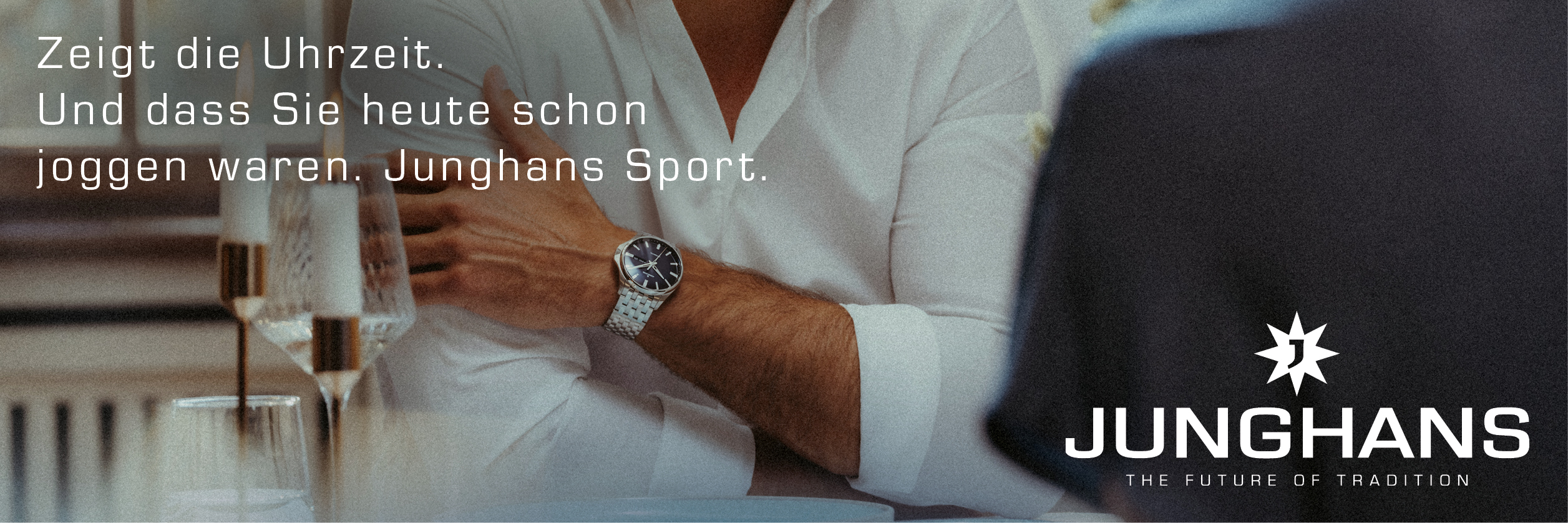 Ein Mann mit zurückgelehntem Arm trägt ein weißes Hemd und eine blaue Uhr, wirkt entspannt
