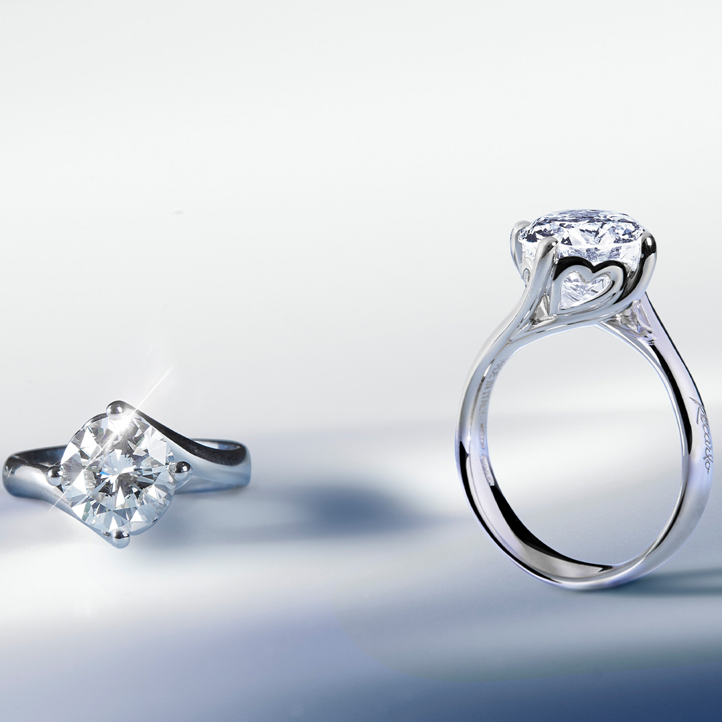 Zwei silberne Ringe mit großen funkelnden Diamanten auf glattem Untergrund