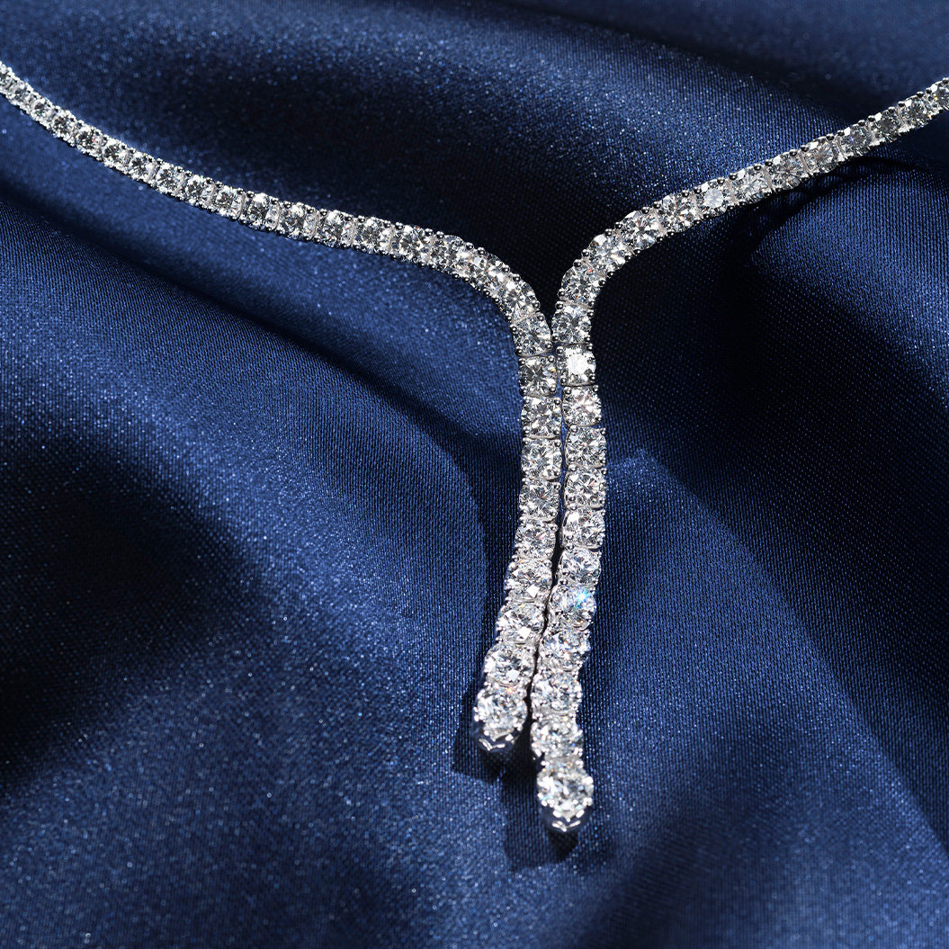 Eine funkelnde Diamantkette liegt elegant auf dunkelblauem glänzendem Stoff