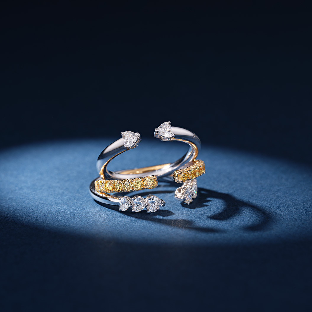 Zwei elegante silberne Ringe mit funkelnden weißen und gelben Edelsteinen auf dunklem Hintergrund