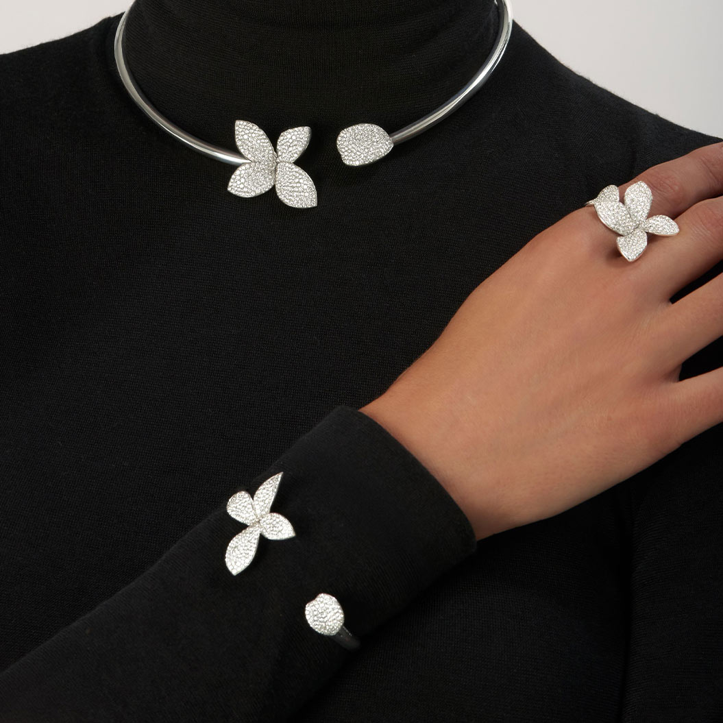 Eine Person mit schwarzem Rollkragenpullover trägt silbernen Schmuck mit Blattmotiven