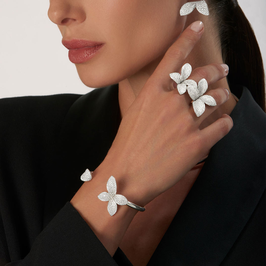 Eine Frau mit neutralem Gesichtsausdruck trägt funkelnden floralen Silberschmuck