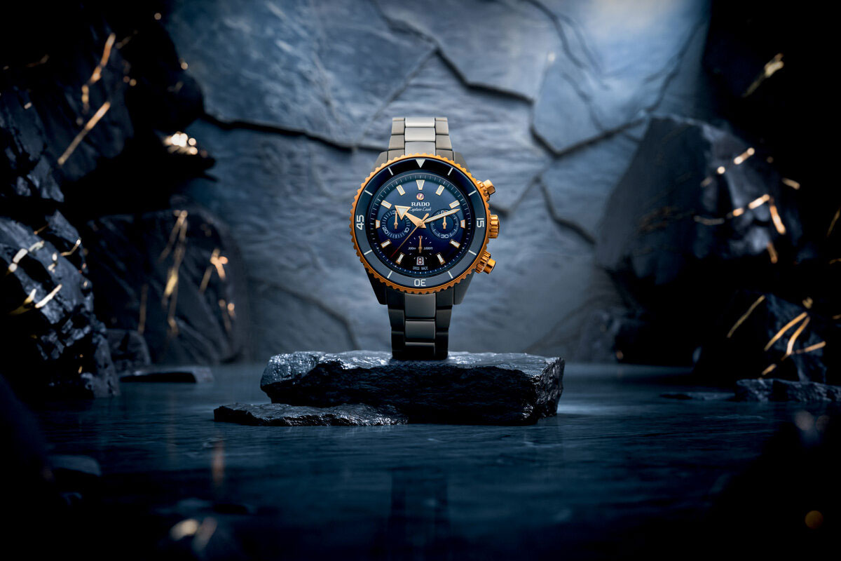 Gold blaue Armbanduhr mit kühlem Glanz auf Felsblock vor Steinwand
