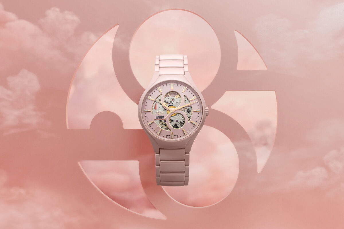 Rosafarbene Armbanduhr mit Chronograph vor wolkigem Hintergrund, elegant schimmernd