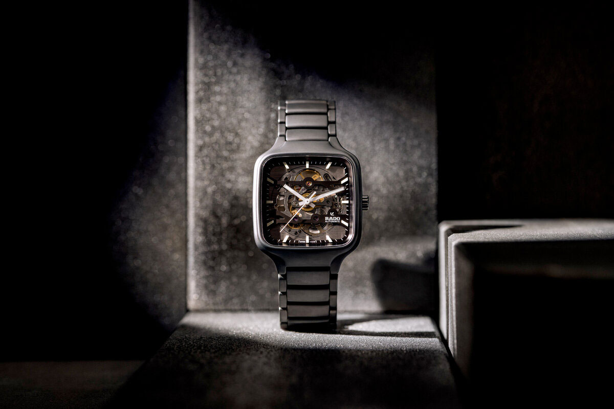 Schwarze Armbanduhr mit Metallband und skelettiertem Zifferblatt im Licht